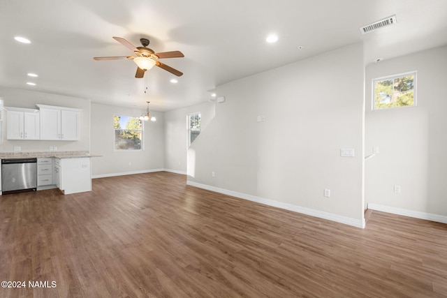 unfurnished living room featuring ceiling fan with notable chandelier and dark hardwood / wood-style flooring