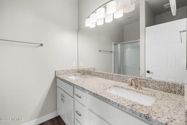 bathroom featuring a shower with shower door and vanity