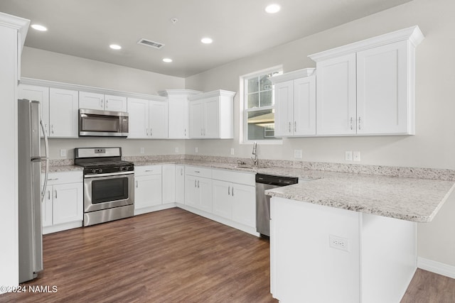 kitchen with kitchen peninsula, dark wood-type flooring, white cabinetry, light stone countertops, and stainless steel appliances