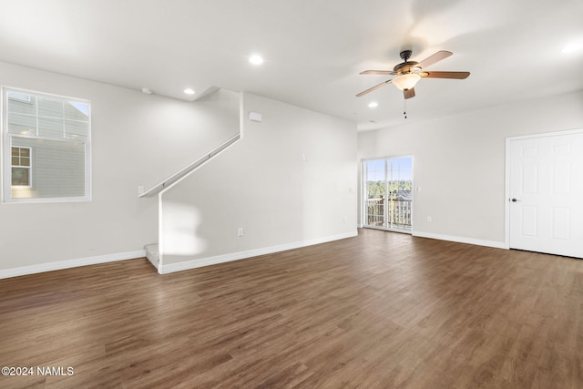 unfurnished living room featuring ceiling fan and dark wood-type flooring