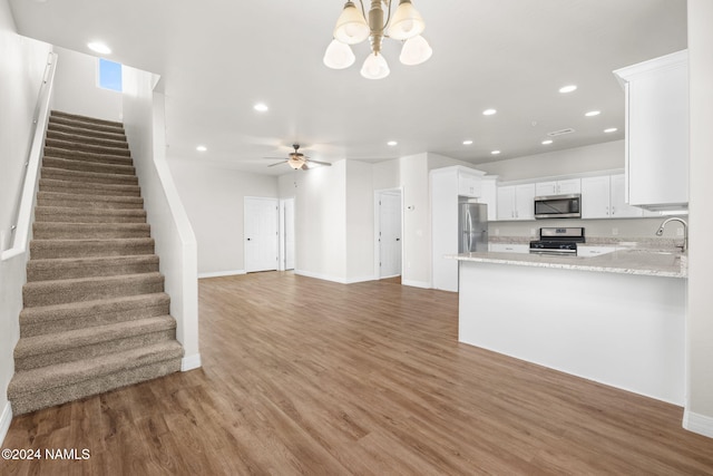 kitchen featuring dark wood-type flooring, white cabinetry, stainless steel appliances, kitchen peninsula, and ceiling fan