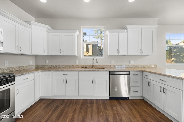 kitchen featuring light stone countertops, appliances with stainless steel finishes, dark wood-type flooring, white cabinetry, and sink