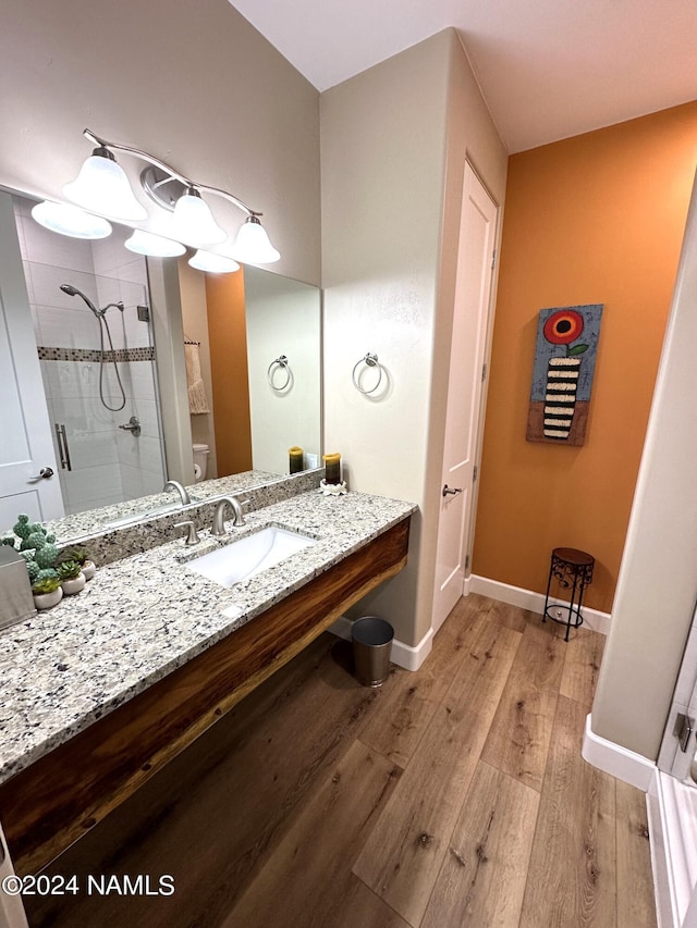 bathroom with sink, hardwood / wood-style flooring, a shower with door, and toilet