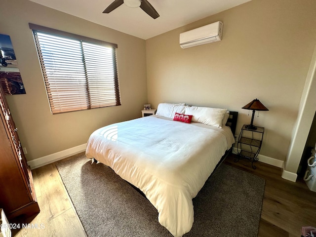 bedroom with dark hardwood / wood-style floors, an AC wall unit, and ceiling fan