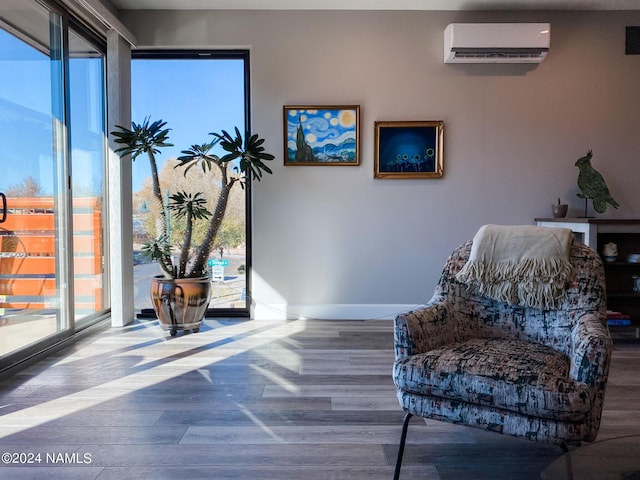 living area featuring hardwood / wood-style floors and a wall unit AC