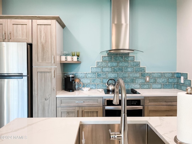 kitchen featuring light stone countertops, ventilation hood, backsplash, stainless steel appliances, and light brown cabinets