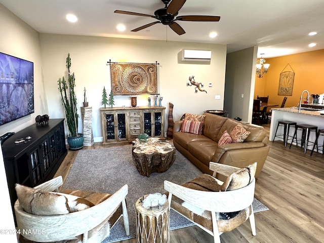 living room featuring ceiling fan with notable chandelier, sink, hardwood / wood-style floors, and a wall mounted air conditioner