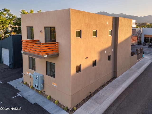 property exterior at dusk featuring a balcony