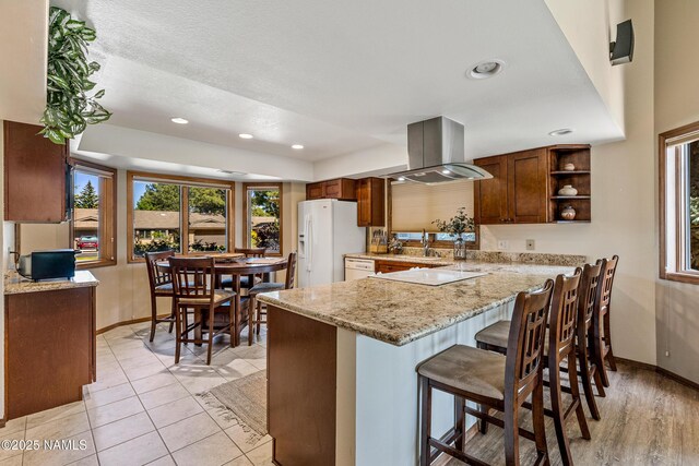 2303 N Plateau Dr, Flagstaff, AZ 86004 - kitchen featuring island range hood, white appliances, a kitchen bar, recessed lighting, and a peninsula