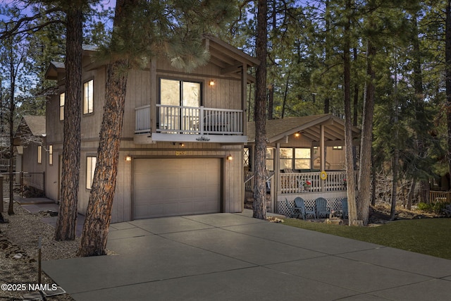 chalet / cabin featuring an attached garage, covered porch, and concrete driveway