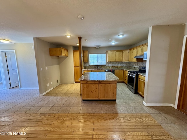 7840 Cowboy Way, Flagstaff, AZ 86004 - kitchen with gas range, dishwashing machine, under cabinet range hood, a center island, and a sink
