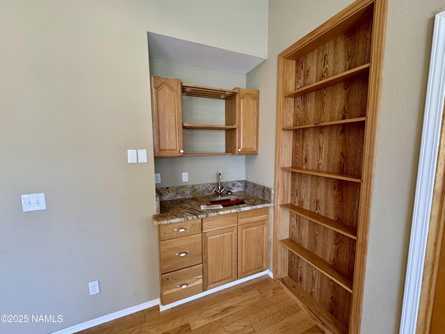 7840 Cowboy Way, Flagstaff, AZ 86004 - kitchen featuring open shelves, light wood finished floors, a sink, and light stone countertops