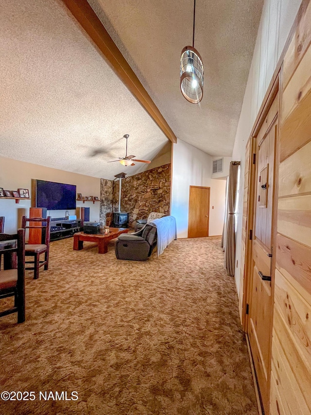 3153 Pinetree Dr, Williams, AZ 86046 - living area featuring a textured ceiling, carpet flooring, a wood stove, lofted ceiling, and ceiling fan