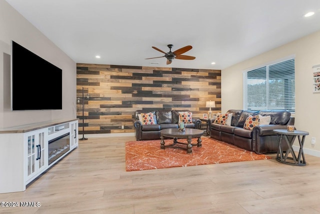 living room featuring ceiling fan, wood walls, and light hardwood / wood-style flooring