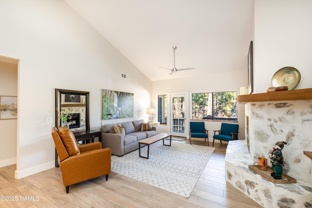 living room featuring high vaulted ceiling, ceiling fan, and light wood-type flooring