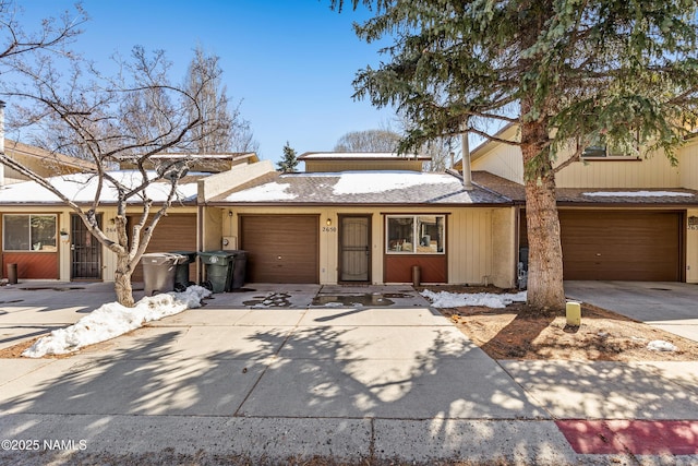 view of property featuring concrete driveway, a garage, and a shingled roof