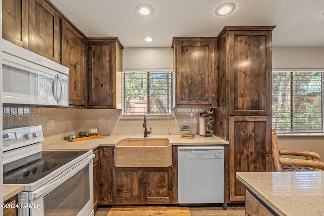 kitchen with sink, dark brown cabinets, white appliances, and a healthy amount of sunlight