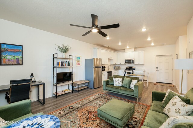 living room featuring ceiling fan, sink, a textured ceiling, and dark hardwood / wood-style flooring