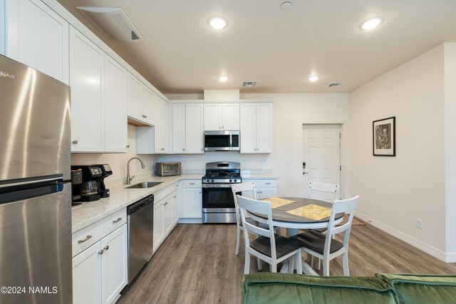 kitchen with light stone countertops, white cabinetry, appliances with stainless steel finishes, and sink