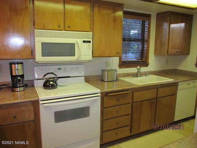2422 N Whispering Pines Way, Flagstaff, AZ 86004 - kitchen featuring white appliances, a sink, backsplash, and light countertops