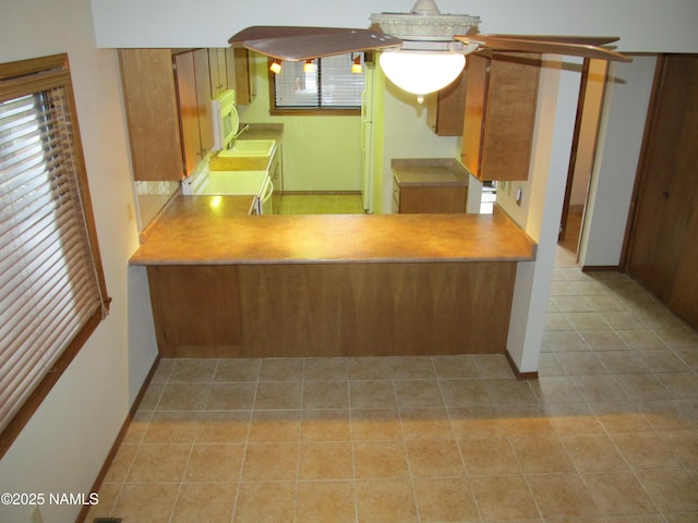 2422 N Whispering Pines Way, Flagstaff, AZ 86004 - kitchen featuring range, white microwave, tile patterned flooring, a sink, and brown cabinetry