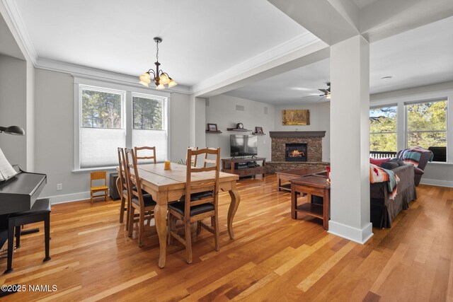 dining area with crown molding, light wood-style flooring, a fireplace, and baseboards