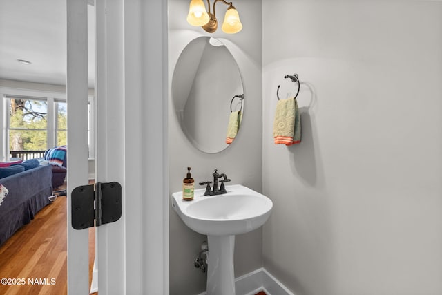 bathroom featuring a notable chandelier, baseboards, and wood finished floors