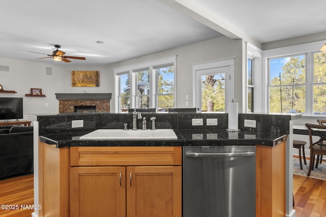 kitchen featuring a healthy amount of sunlight, open floor plan, dishwasher, light wood-type flooring, and a sink