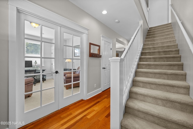 staircase with wood finished floors, recessed lighting, and french doors