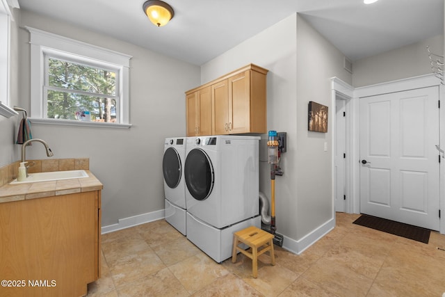 washroom with washing machine and dryer, cabinet space, baseboards, and a sink