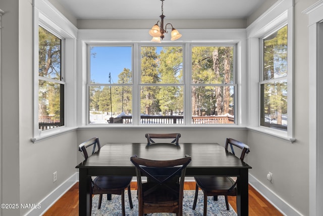 dining area featuring baseboards, an inviting chandelier, and wood finished floors