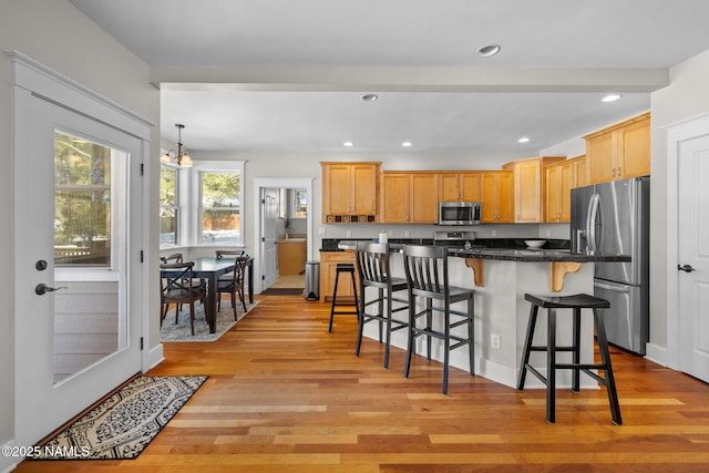 kitchen featuring a breakfast bar area, recessed lighting, light wood-style flooring, and appliances with stainless steel finishes