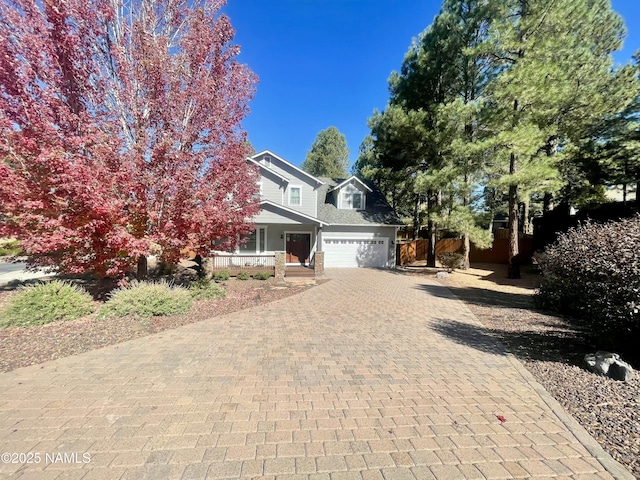 view of side of property with a garage, covered porch, and decorative driveway