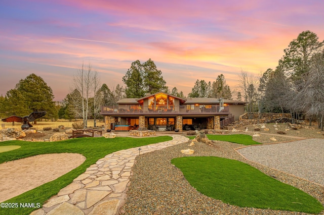 view of front of property featuring a wooden deck, a lawn, and a patio area