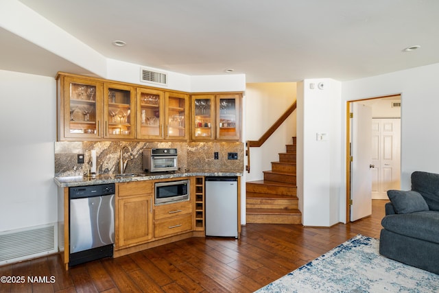 kitchen with stone counters, sink, backsplash, dark hardwood / wood-style flooring, and stainless steel appliances