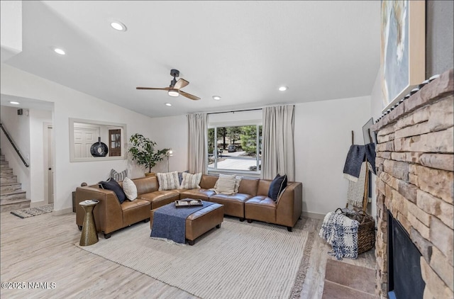 living area with wood finished floors, recessed lighting, stairway, a stone fireplace, and vaulted ceiling