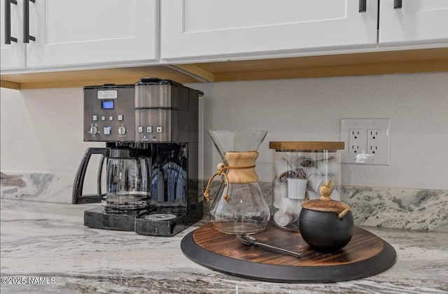 details featuring white cabinets and light stone countertops