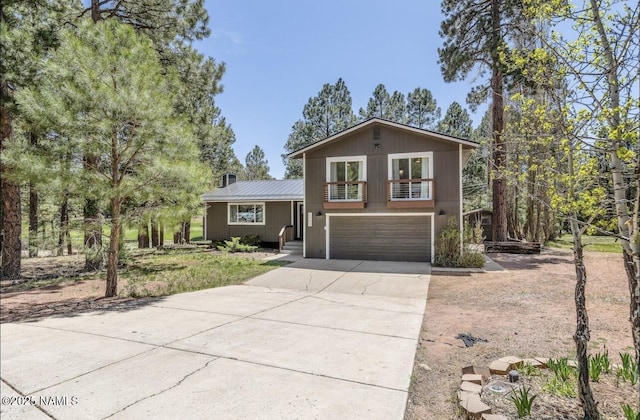 tri-level home with driveway, an attached garage, and metal roof