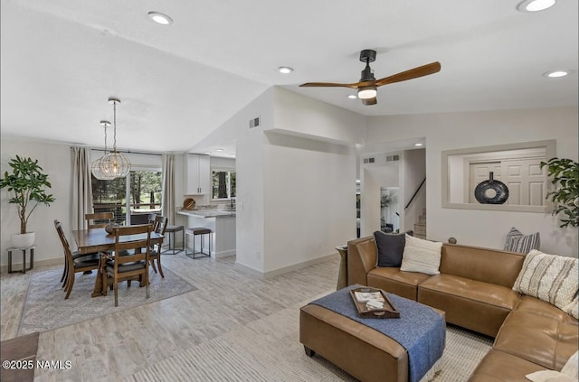 living room with visible vents, baseboards, stairs, and vaulted ceiling