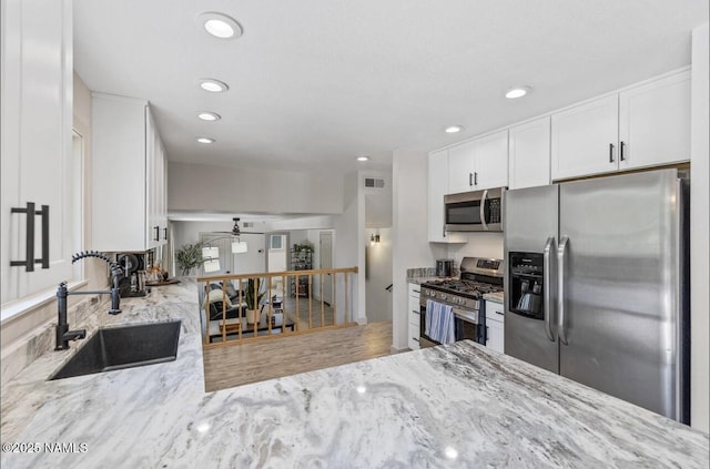 kitchen featuring a sink, white cabinets, light stone countertops, and stainless steel appliances