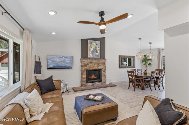 living area featuring recessed lighting, lofted ceiling, a stone fireplace, and ceiling fan