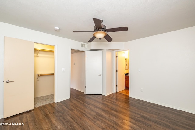 unfurnished bedroom featuring ceiling fan, dark hardwood / wood-style floors, a closet, and a walk in closet