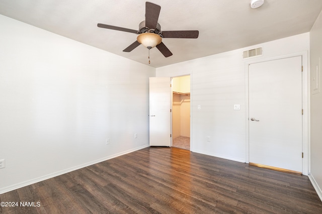 unfurnished bedroom with a closet, ceiling fan, a spacious closet, and dark hardwood / wood-style floors