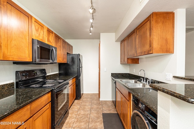 kitchen featuring black appliances, washer / clothes dryer, dark stone counters, sink, and rail lighting