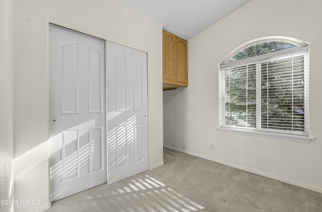 unfurnished bedroom with a closet, lofted ceiling, baseboards, and carpet floors