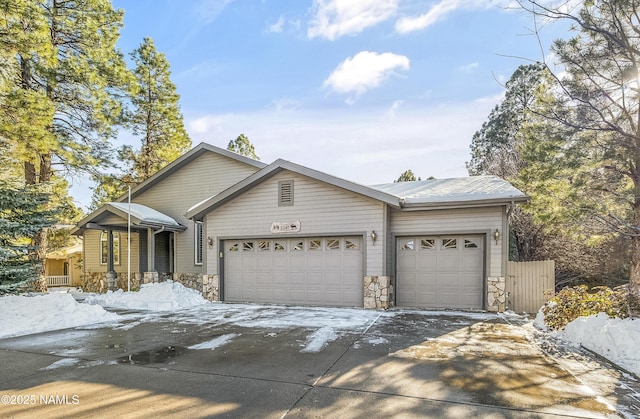 view of front of home featuring stone siding, an attached garage, and driveway