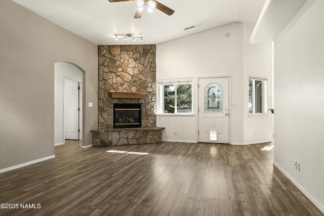 unfurnished living room with a ceiling fan, dark wood-style floors, visible vents, lofted ceiling, and a fireplace