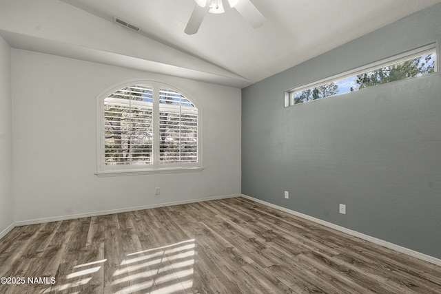 spare room featuring visible vents, baseboards, lofted ceiling, and wood finished floors