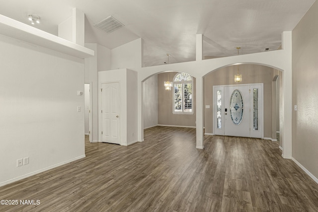 foyer with arched walkways, visible vents, an inviting chandelier, and wood finished floors