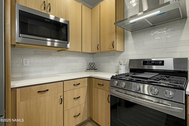 kitchen featuring decorative backsplash, wall chimney range hood, and appliances with stainless steel finishes